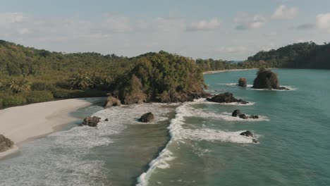 cinematic drone aerial of the waves crashing on the beach on the jungle of costa rica