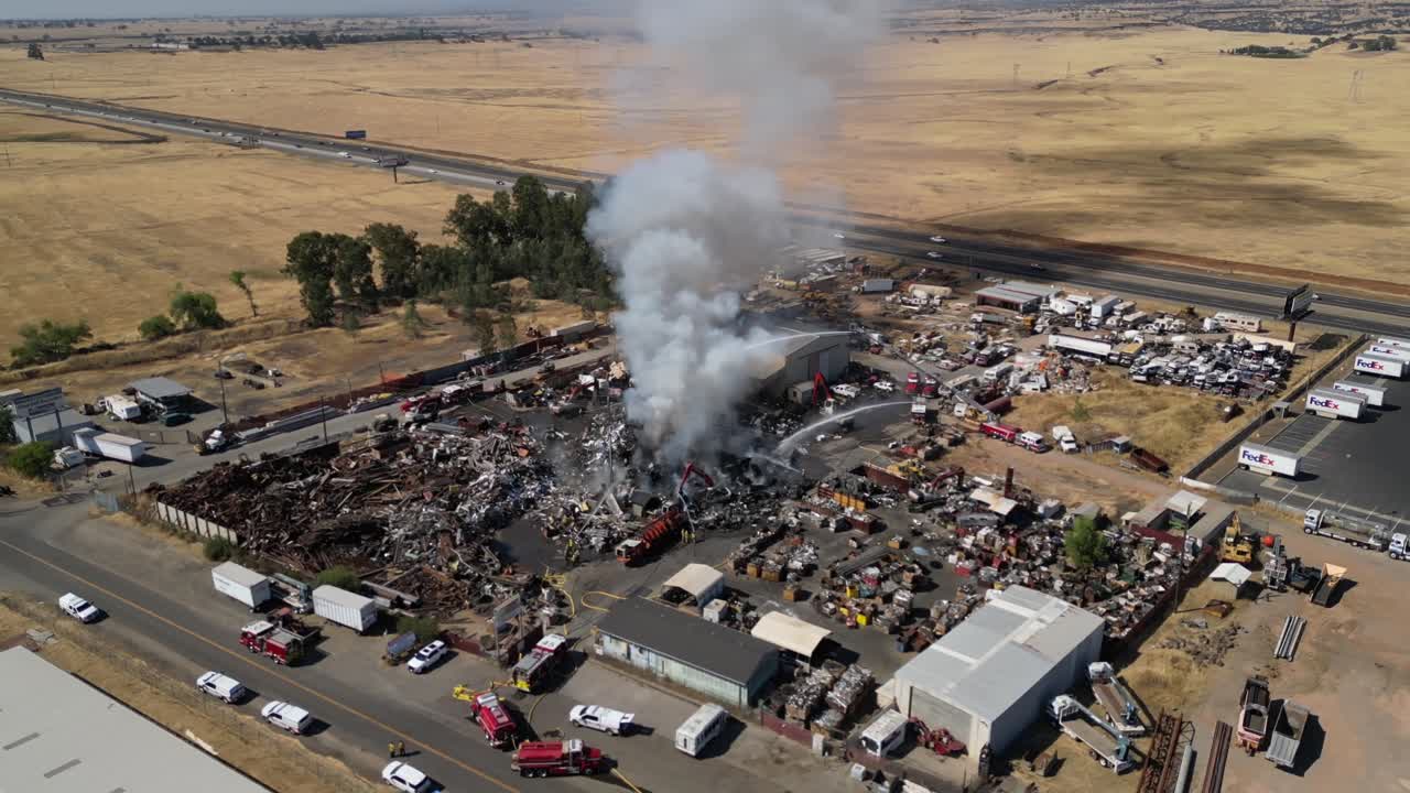 Aerial view of a large junkyard fire with emergency response