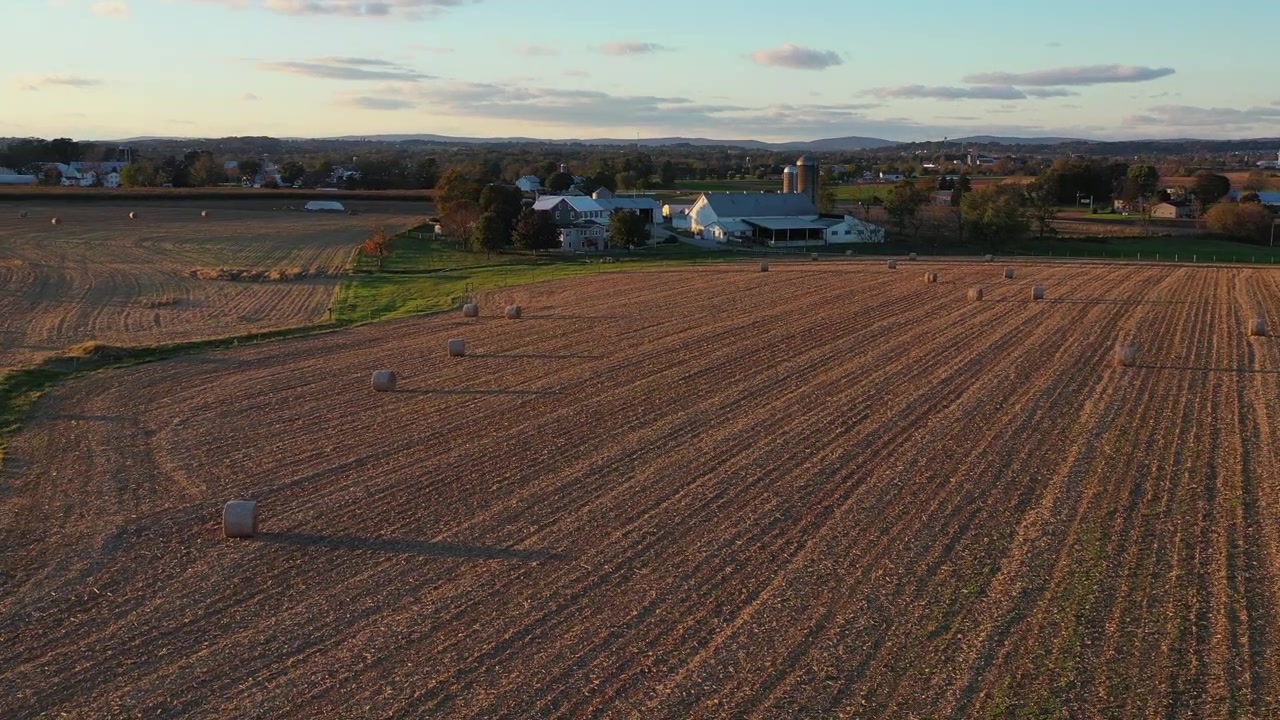 Reversal drone shot over pastures and a farmhouse that reveals a vast farmland