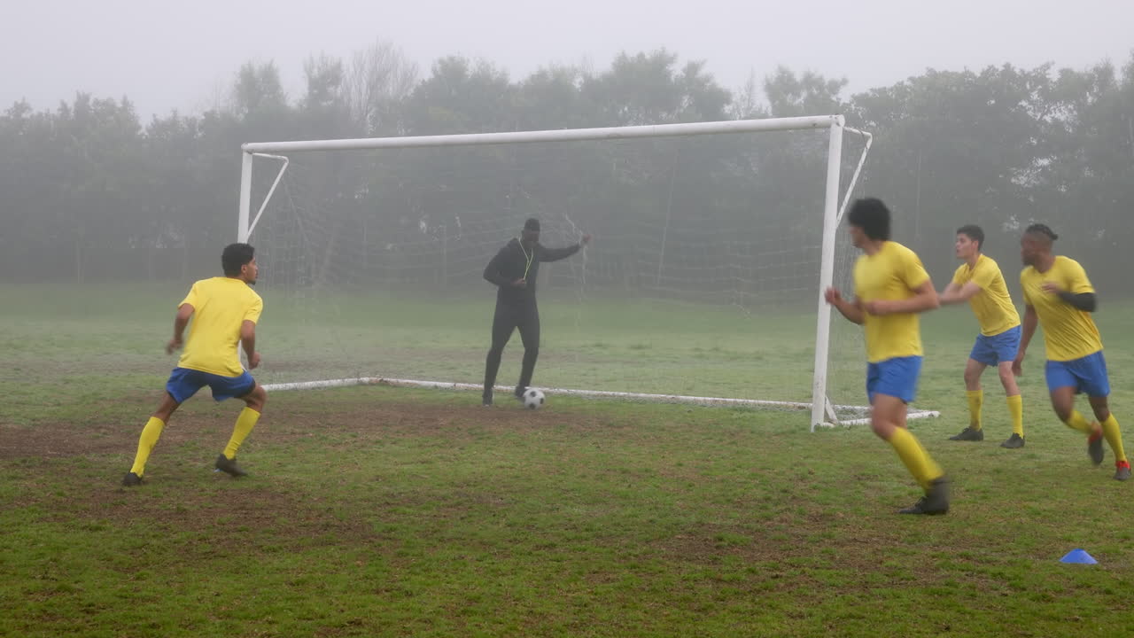 Playing soccer, team practicing drills on foggy field with coach guiding players