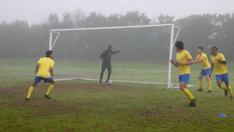 Playing soccer, team practicing drills on foggy field with coach guiding players