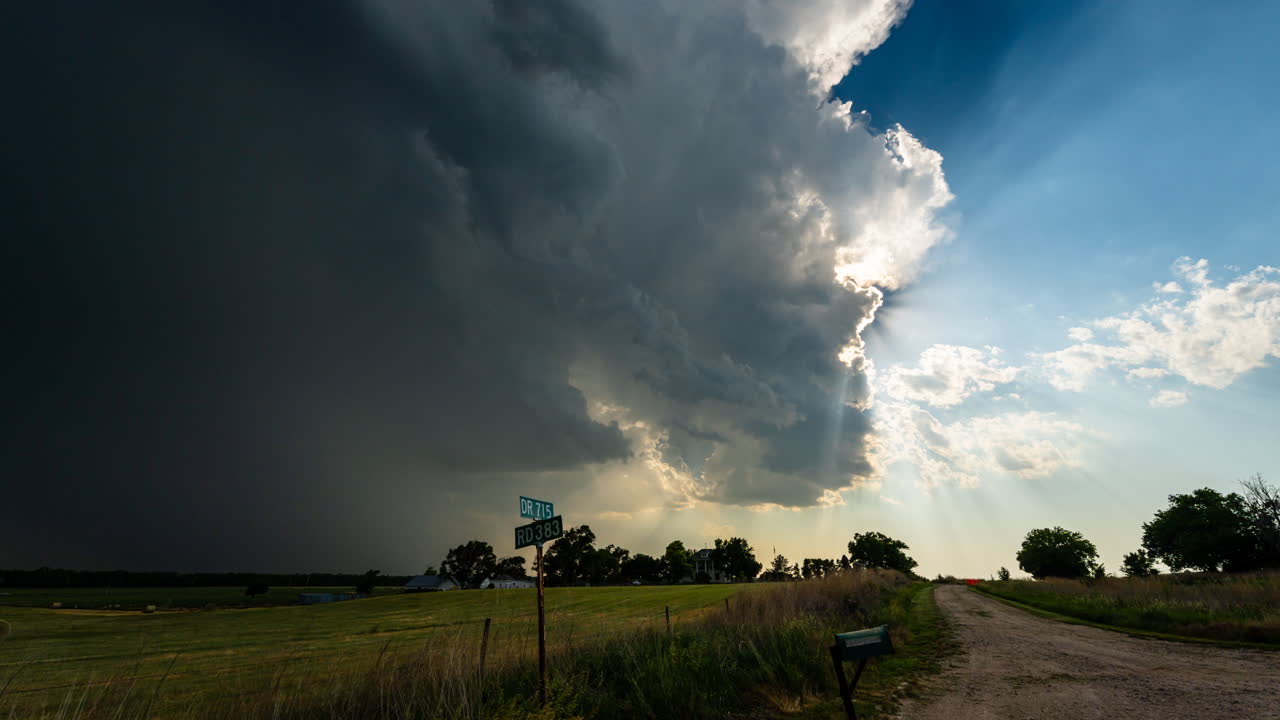 Sun rays shine through storm clouds over a quiet country road time lapse