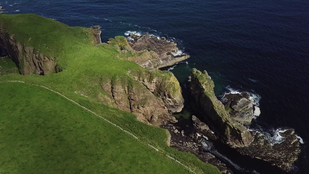 Aerial view of rugged cliffs and seagulls with waves hitting the rocks on the scottish northshore