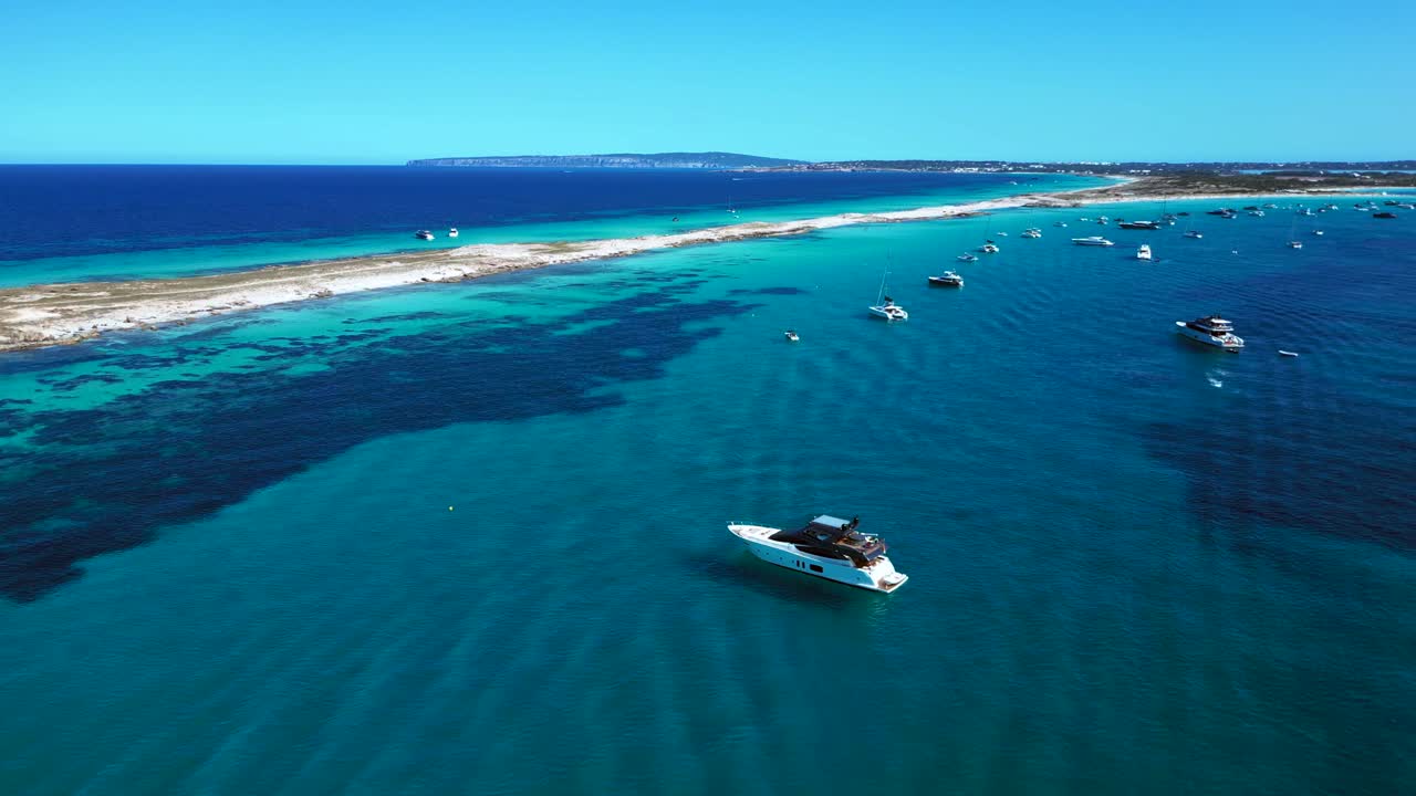 Ibiza Formentera coastline with numerous yachts and boats navigating crystal clear turquoise waters. Dramatic aerial view flight overflight flyover drone