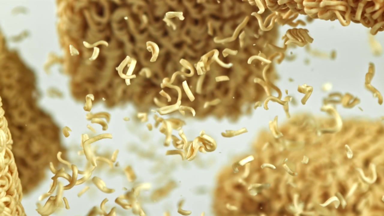 Noodles ramen istantanei secchi che cadono e si rompono al rallentatore.
