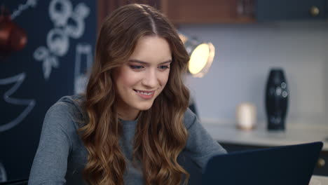 cheerful woman reading message on laptop indoors