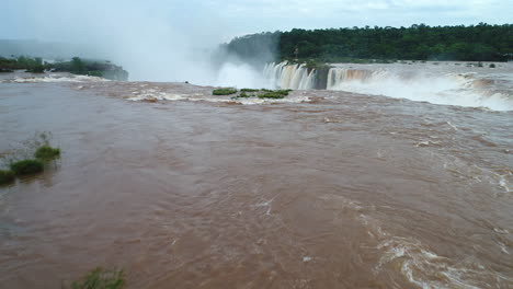 Drone's-low-flight-over-the-river,-revealing-the-immense-Devil's-Throat-in-Iguazu-Falls