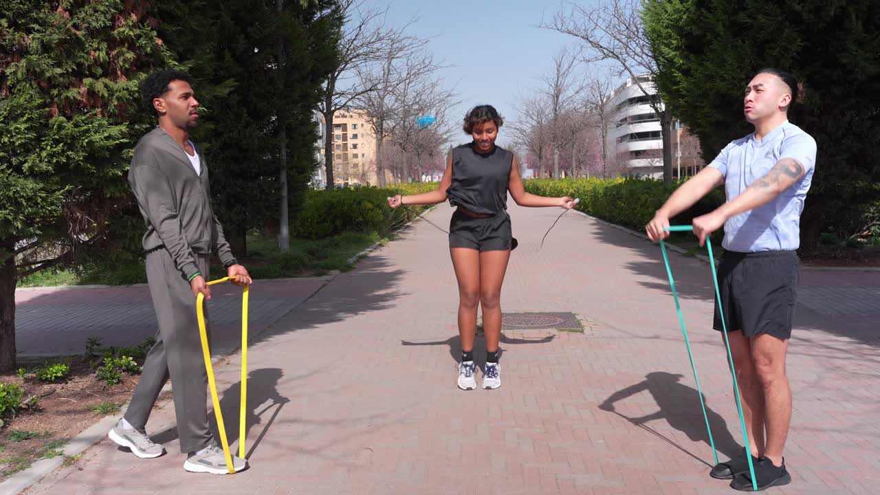 Three Friends Exercising Outdoors with Jump Rope and Resistance Bands