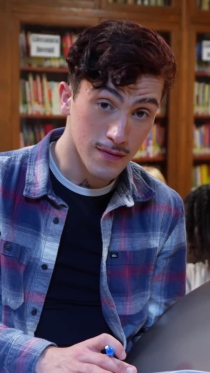 Jovem Escrevendo num Caderno e Sorrindo numa Biblioteca