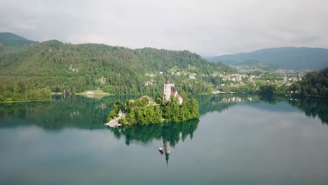 drone shot rising with assumption of maria church in the middle of lake bled in slovenia