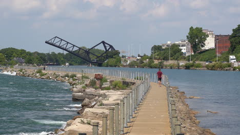 un hombre caminando en un muelle que separa el río niagara y el canal erie