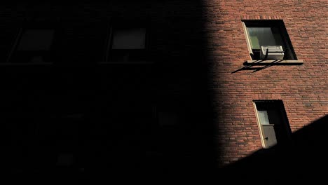 Sombras-En-La-Pared-Del-Edificio-De-Ladrillo-Con-Ventanas-A-Medida-Que-Desaparece-La-Luz-Del-Sol