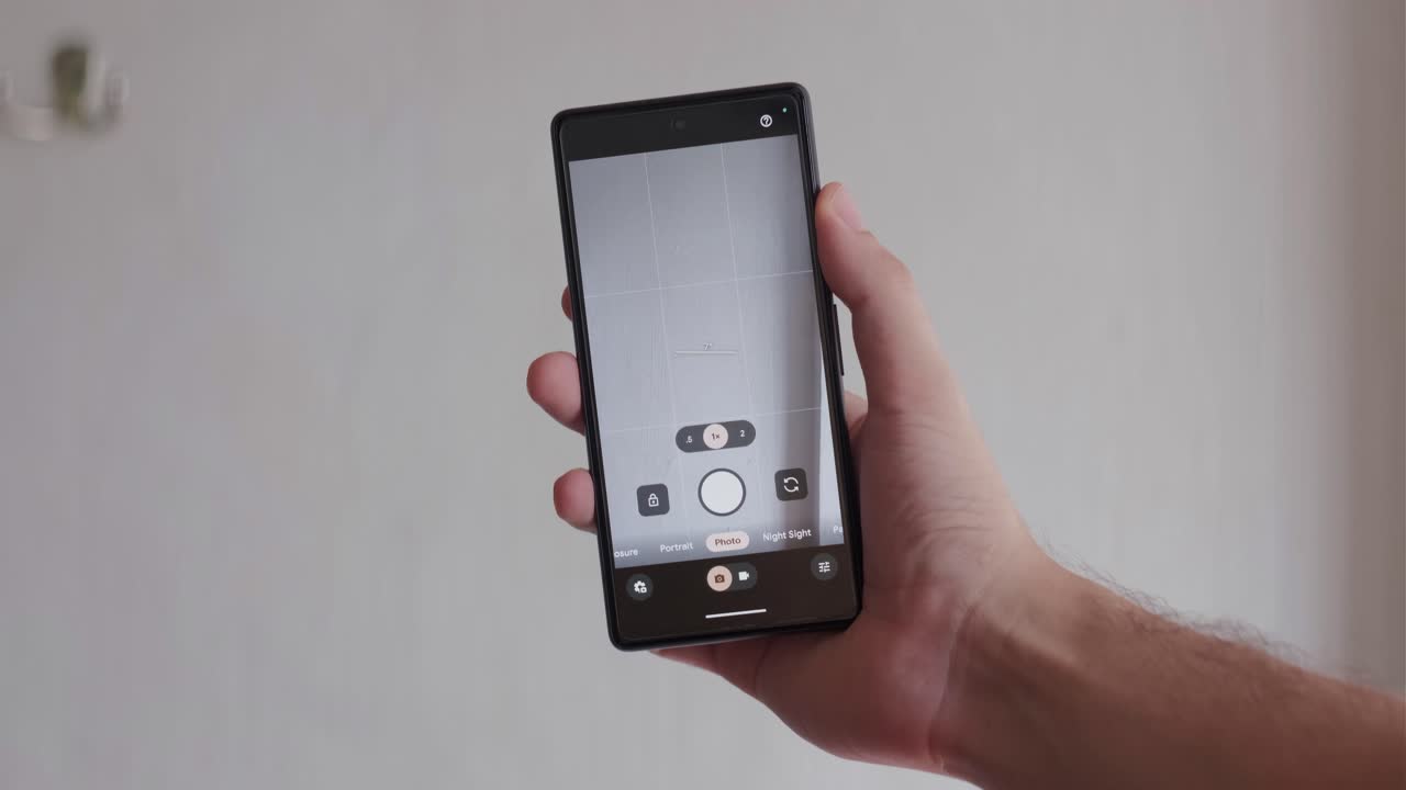 Immagine statica di una mano che tiene in mano uno smartphone moderno in un ambiente interno, con l'app fotocamera aperta sullo schermo