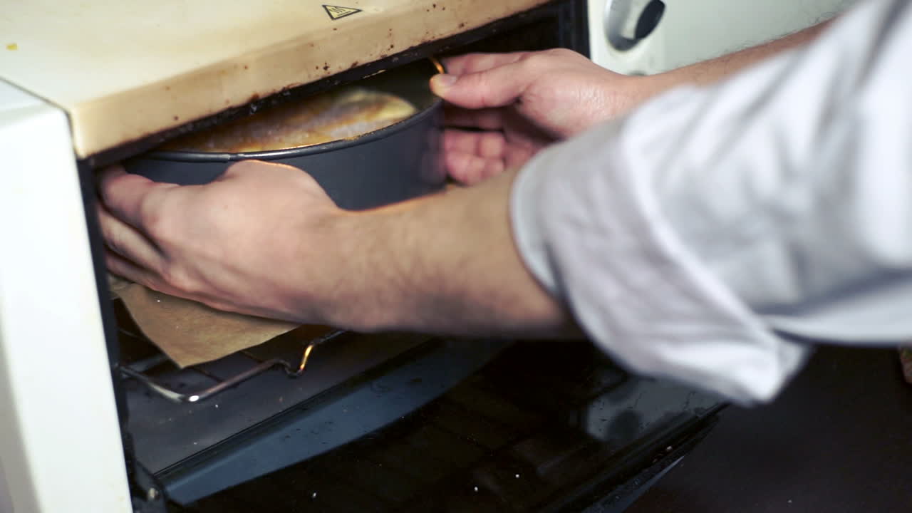 Mann schiebt Apfelkuchen in den Ofen. Kuchen backen. Hausbacken. Kleiner Ofen in der Bäckerei