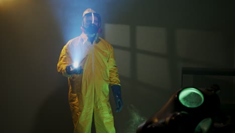 hazmat suit wearing man explores a dark room