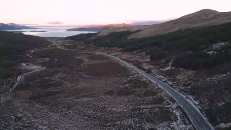 solitary road winding through the rugged terrain of skye at dusk, hinting at adventure, aerial view