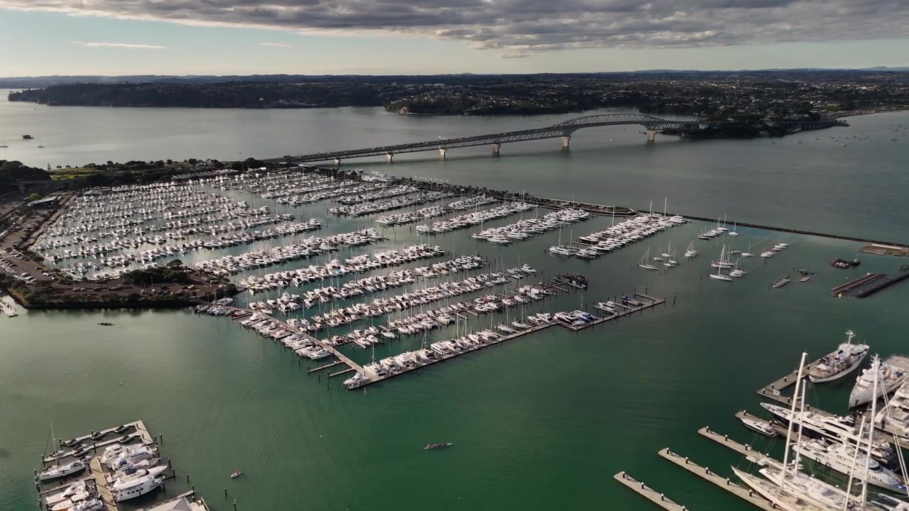 Luxury superyachts in Westhaven Marina and Auckland Harbour Bridge in Auckland, New Zealand. Aerial drone view