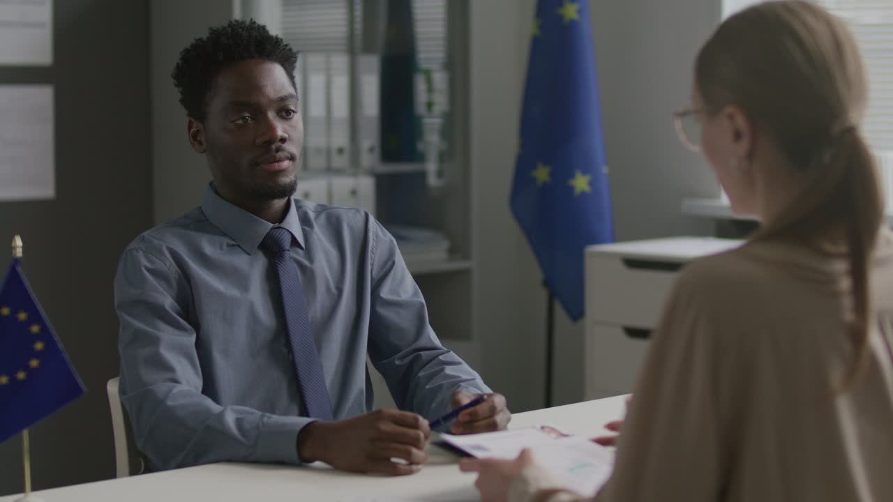 Afroameričan na pohovoru s ženskou vízovou úřednicí na konzulátu EU