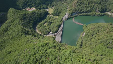 aerial drone fly above dam in kyoto blue water landscape quiet river flow at zen green cedar forest, japanese japan natural environment in kansai daylight