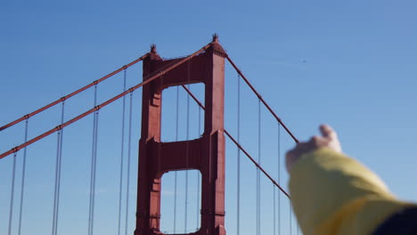 Male-Hand-Pointing-At-Golden-Gate-Bridge-Tower-Against-Blue-Sky-In-San-Francisco,-California