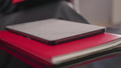 close-up of gray laptop placed on red notebooks and papers on glass desk. organized workspace in corporate office, focusing on productivity tools for business and career management