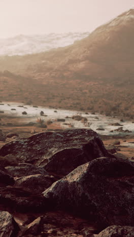 a rugged mountain landscape with a stream in the foreground