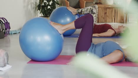 Focused-caucasian-senior-people-exercising-on-mats-with-balls-and-with-female-coach-in-slow-motion