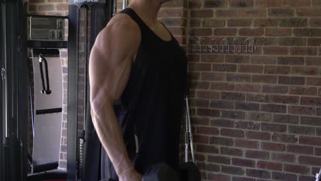 muscly man in home gym exercising single arm forearm bicep curls