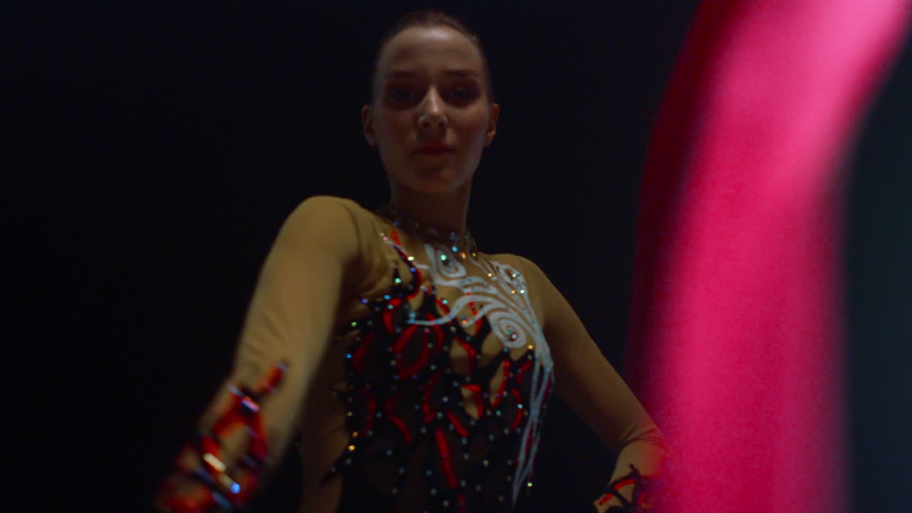 Pretty woman with gymnastic ribbon looking camera. Girl doing gymnastics inside.