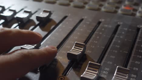 a person adjusting the audio levels on a music mixer