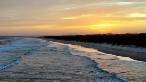 Dawn's-early-light-painting-the-beach-with-warm-hues,-Gentle-waves-caressing-the-shore