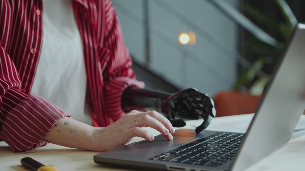 Close-Up of Female Office Worker with Prosthetic Arm Using Laptop