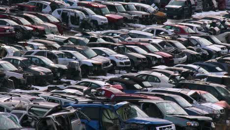 cars sit in rows in a junkyard in the snow 3