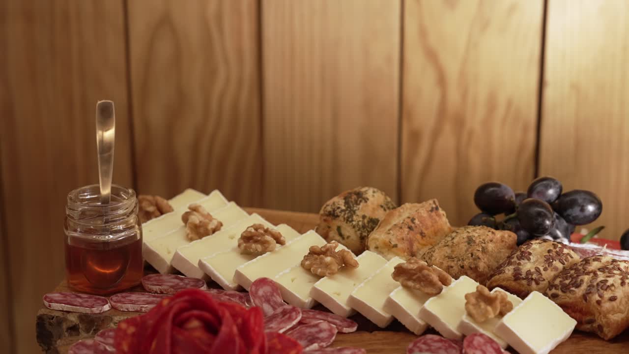 Close up of elegant appetizer platter cheese salami walnuts grapes honey