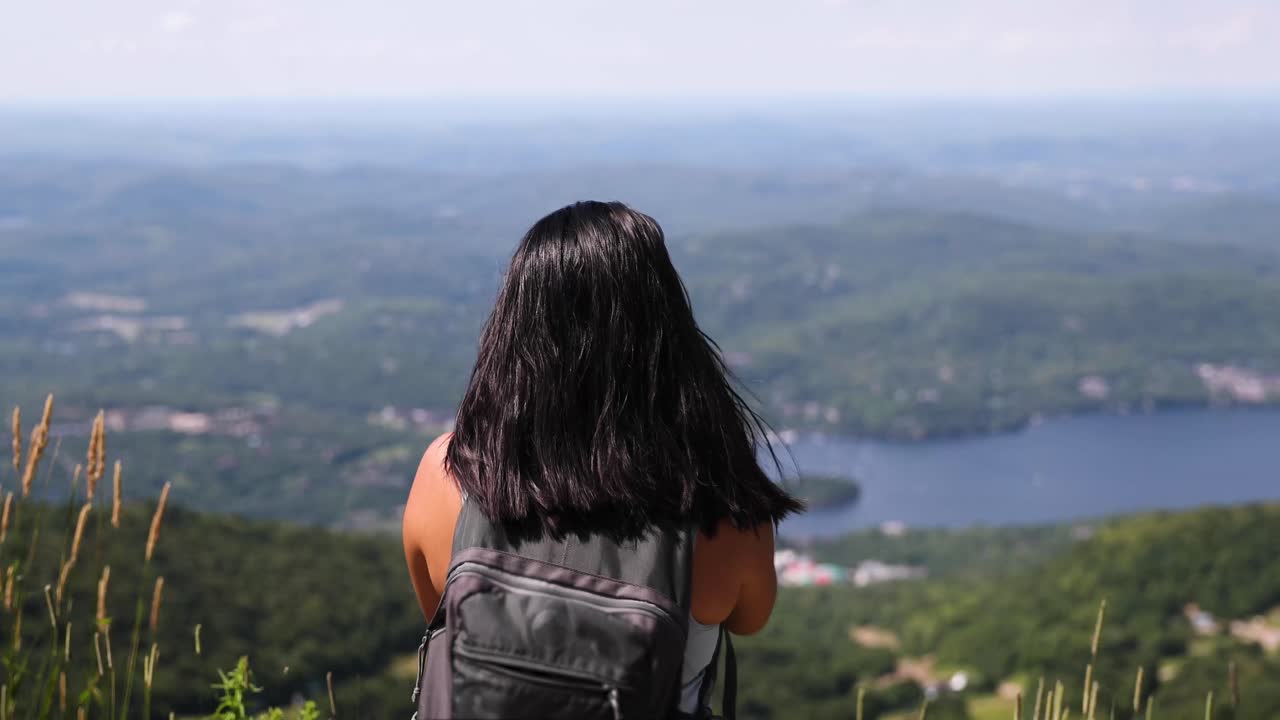 Female hiker looks out over beautiful summer landscape on top of a Mt