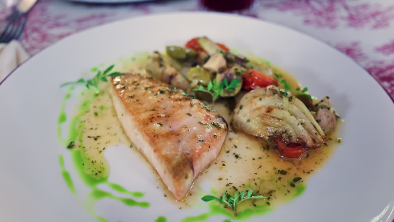 Close up of grilled salmon with vegetables on a white plate at a restaurant