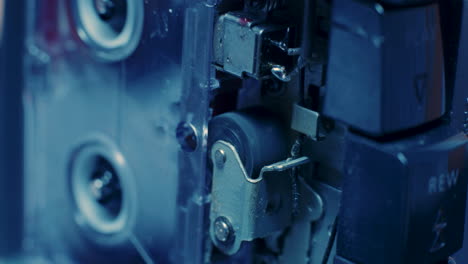cableado expuesto y rodillo de arrastre visibles dentro de la grabadora de microcassette bajo una luz azul fría