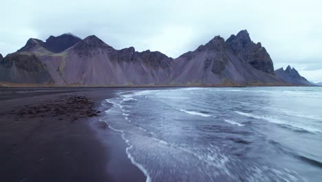 aerial: la montaña vestrahorn en el sureste de islandia cerca de hofn está entre la costa del océano y tussocks