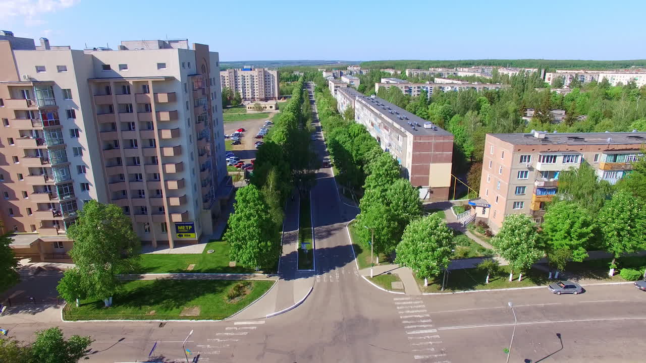 Empty crossroads in the modern Ukrainian city. Drone shot rising over the city on summer day. Green nature at backdrop.