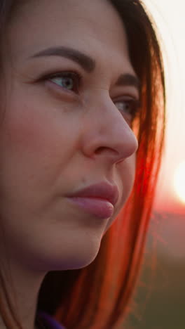 upset woman stands against red evening sun closeup. dark haired lady thinks about life difficulties at tranquil countryside. mental health condition