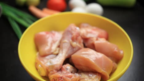 raw chicken curry cut pieces in a yellow bowl closeup, leg piece, thighs