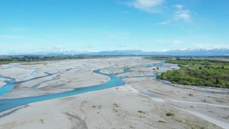 Volando-Alto-Río-Arriba-Sobre-El-Trenzado-Río-Waimakariri-En-Nueva-Zelanda---Numerosos-Canales-De-Hermosas-Aguas-Turquesas,-Cielo-Azul-Claro-Y-Montañas-A-Lo-Lejos