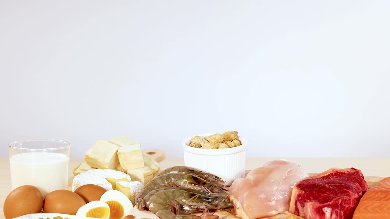 A variety of protein-rich foods including nuts, eggs, dairy, and meats are neatly arranged on a table
