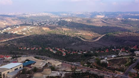 aerial view of a settlement and distant city in a hilly landscape