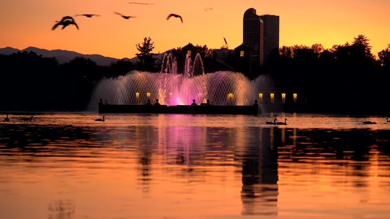 fuente de agua iluminada contra un fondo de horizonte de denver al atardecer