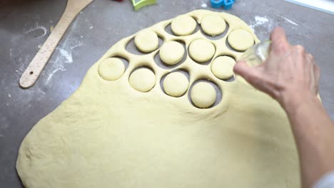 female hands cutting circle shapes from the raw dough