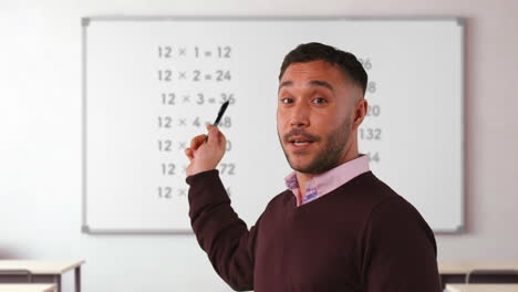 fotografía de cerca de un maestro de sexo masculino maduro en el aula de pie frente a la junta enseñando matemáticas elementales lección 1