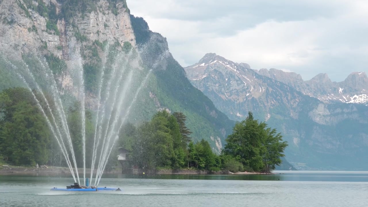 Sistema di aerazione dell'acqua in funzione su un lago con montagne, creando una composizione equilibrata dal punto di vista ambientale e paesaggistico.