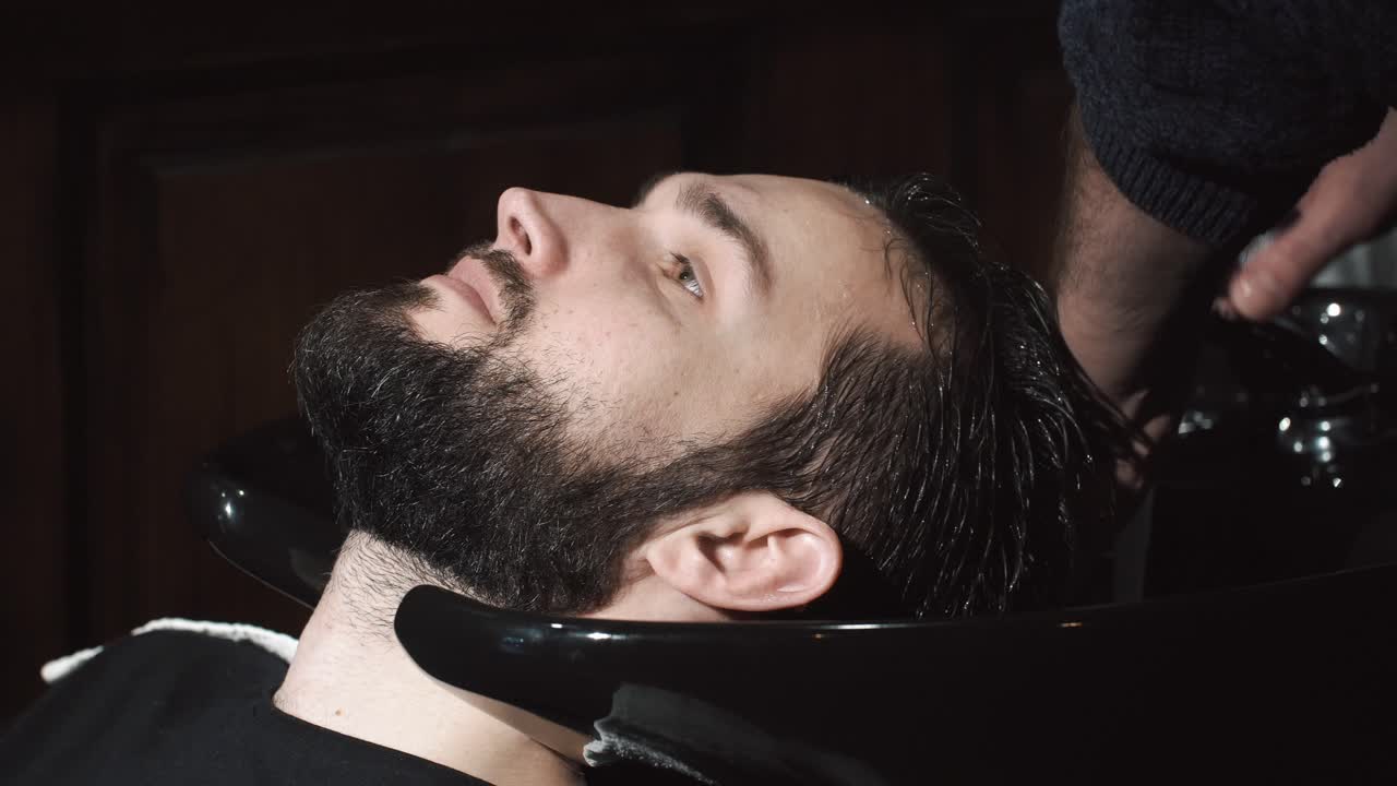 Mand får vasket hår ved en barbersalonvask.