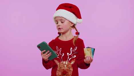 Child-girl-in-Christmas-sweateruse-mobile-cell-phone,-plastic-credit-bank-cards,-win,-calebrate,-wow